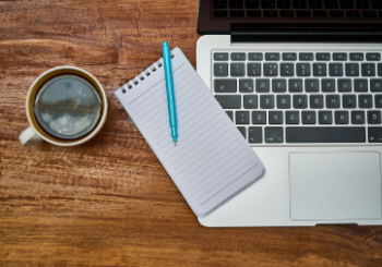 Laptop, notepad and coffee on desk