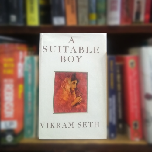 Shows based on books: front cover of A Suitable Boy, white with illustration of a young woman, sitting on Library shelf