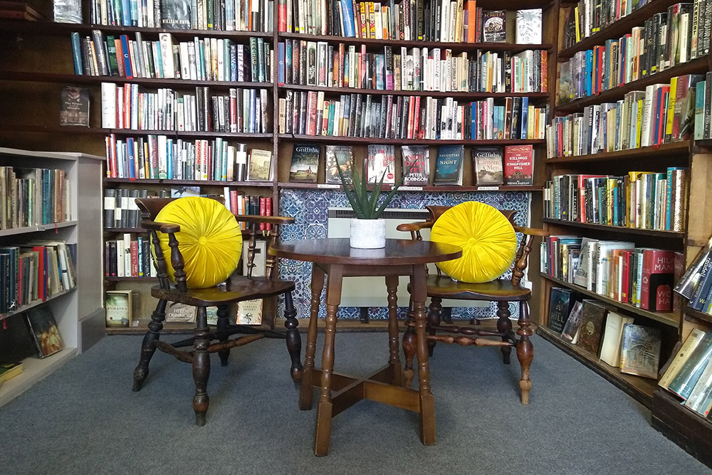 The Library: Two wooden chairs with yellow cushions and a small round table