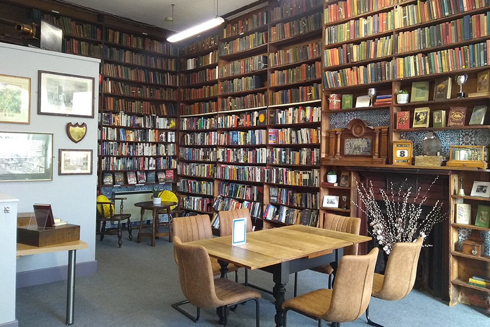 The Library: Floor-to-ceiling bookcases with a table and chairs, seating area and fireplace