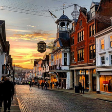 Autumn brochure: Looking down Guildford high street at sunset; cobbled paving with the prominent Guildhall clock. 