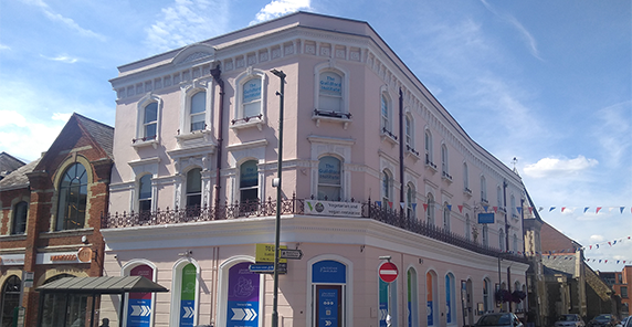Photo of exterior of The Guildford Institute building which is light pink, with sash windows and burgundy railings.