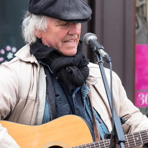 Dean Dyson singing and playing a guitar